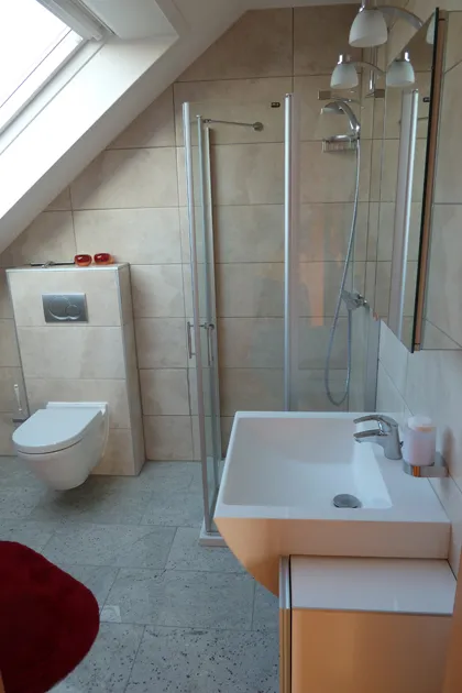 Modernes Tageslichtbad der Ferienwohnung in Pohlheim mit Dusche, Hänge-WC und Waschbecken unter der Dachschräge
