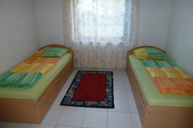 Schlafzimmer der Monteurwohnung in Pohlheim mit zwei Einzelbetten und farbiger Bettwäsche